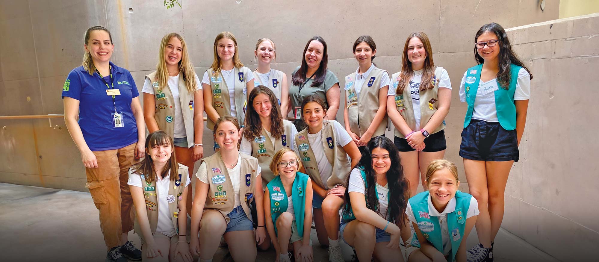 Two Springs Preserve staff members pose with a group of 13 Girl Scouts from Troop 777, who are participating in an outdoor activity and wearing their iconic uniforms.